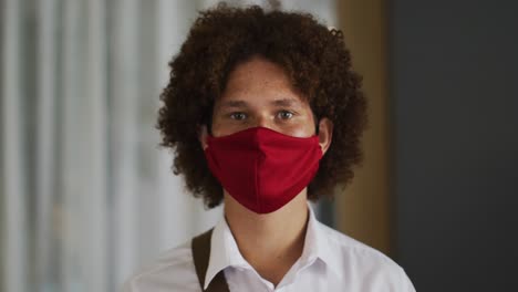 Portrait-of-mixed-race-man-with-curly-hair-wearing-red-face-mask