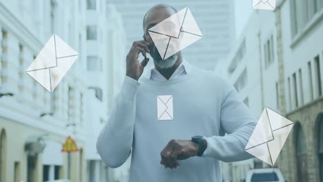 Animation-Digitaler-Briefumschlagsymbole-über-Einem-Afroamerikanischen-Mann,-Der-Sein-Smartphone-In-Der-Stadt-Benutzt