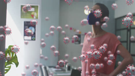 Animation-Von-Covid-19-Zellen-über-Einer-Frau-Im-Büro-Mit-Gesichtsmaske