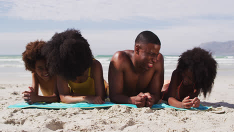 Portrait-of-african-american-parents-and-two-children-lying-on-a-towel-at-the-beach-smiling