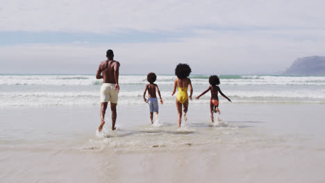 Padres-Afroamericanos-Y-Dos-Niños-Corriendo-En-La-Playa.