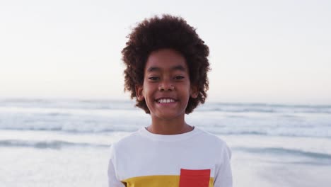 Porträt-Eines-Afroamerikanischen-Jungen,-Der-Lächelt,-Während-Er-Am-Strand-Steht
