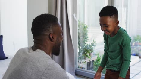 African-american-father-helping-his-son-with-getting-dressed-in-bedroom