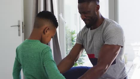 African-american-father-helping-his-son-with-getting-dressed-in-bedroom