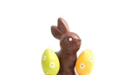 Animation-of-chocolate-easter-bunny-and-eggs-on-white-background