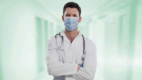Portrait-of-caucasian-male-doctor-wearing-face-mask-against-white-background