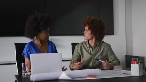 Diverse-male-and-female-business-colleagues-in-discussion-at-work-using-laptop-computer