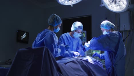 Diverse-surgeons-wearing-surgical-caps-and-face-masks-in-operating-theatre-in-hospital