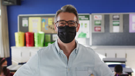 Portrait-of-caucasian-male-teacher-wearing-face-mask-in-the-class-at-school