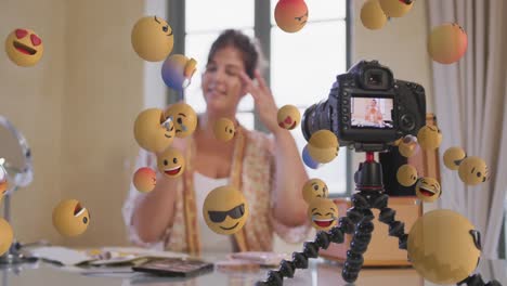 Animation-of-emoji-icons-over-female-vlogger-in-camera-viewer-recording-vlog-at-home