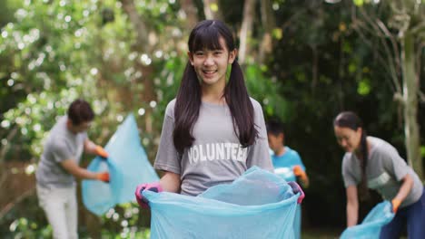 Lächelndes-Asiatisches-Mädchen-Im-Freiwilligen-T-Shirt-Mit-Müllsack-Zum-Sammeln-Von-Plastikmüll