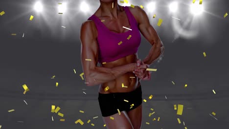 Golden-confetti-falling-over-mid-section-of-female-athlete-flexing-her-biceps-against-sports-stadium