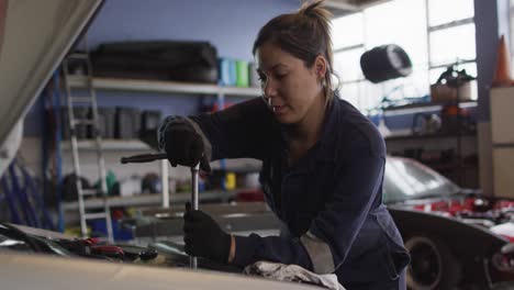 Mecánica-Femenina-Usando-Una-Llave-Para-Reparar-Un-Automóvil-En-Una-Estación-De-Servicio-De-Automóviles