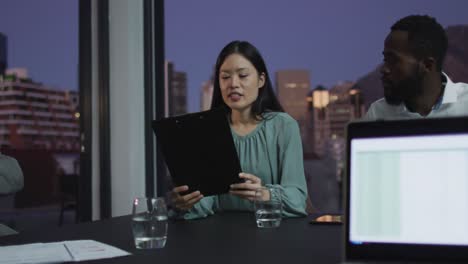 Video-Einer-Asiatischen-Geschäftsfrau,-Die-Bei-Einem-Abendlichen-Bürotreffen-Mit-Verschiedenen-Kollegen-Spricht