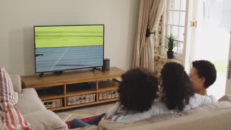 Composite-of-happy-family-sitting-at-home-together-watching-running-athletics-event-on-tv