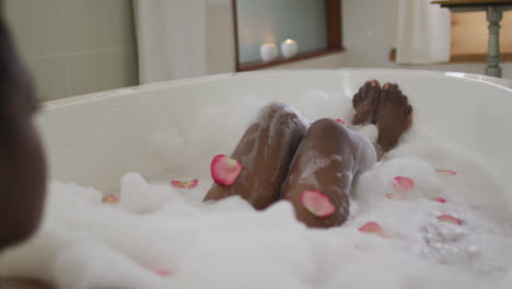 Legs-of-african-american-attractive-woman-taking-bath-with-foam-and-rose-petals
