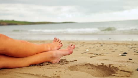Womans-legs-sitting-on-the-beach