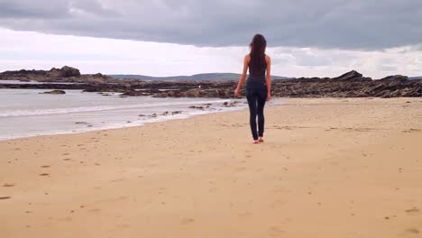 Beautiful-brunette-walking-along-the-water-by-the-beach