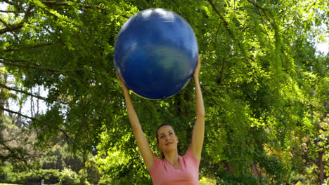 Fitte-Frau,-Die-Im-Park-Einen-Gymnastikball-Hochhebt