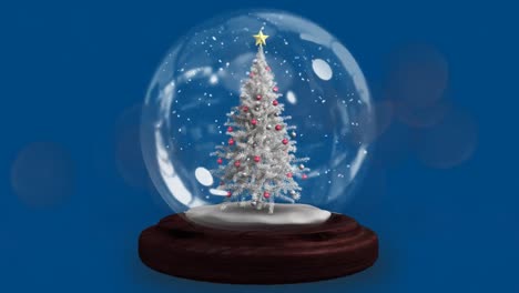 Two-shooting-stars-spinning-around-christmas-tree-in-a-snow-globe-against-blue-background