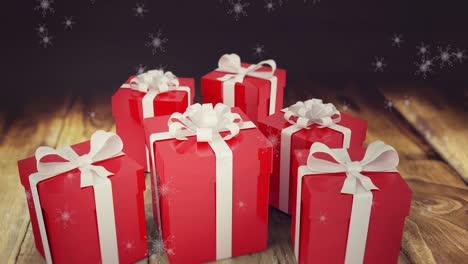 Animation-of-snow-falling-over-presents-on-wooden-background
