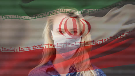 Animation-of-flag-of-iran-waving-over-woman-wearing-face-mask-during-covid-19-pandemic