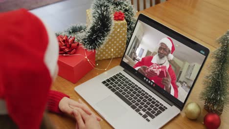 Happy-caucasian-woman-on-video-call-with-santa-claus-at-christmas-time