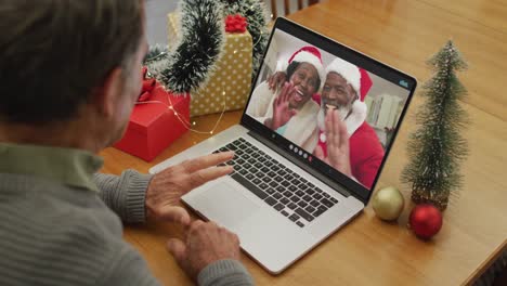 Caucasian-senior-man-on-video-call-with-seniio-friends-at-christmas-time