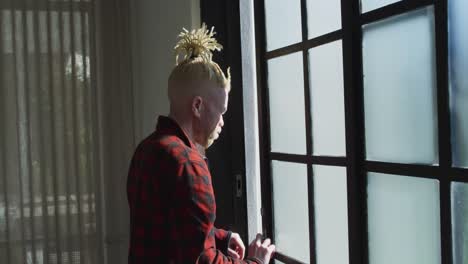 Thoughtful-albino-african-american-man-with-dreadlocks-looking-at-the-window