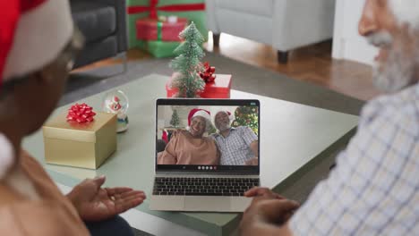 Happy-african-american-couple-on-video-call-on-laptop-with-senior-friends-at-christmas-time