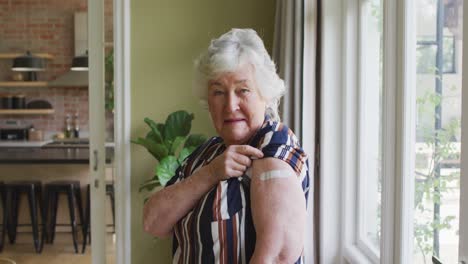 Happy-caucasian-senior-woman-showing-plaster-on-arm-after-covid-vaccination