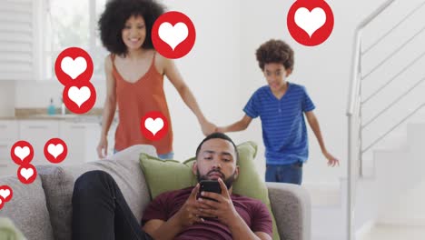 Animation-of-social-media-heart-icons-over-biracial-man-using-smartphone