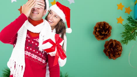 Composition-of-caucasian-couple-in-santa-holding-christmas-present-on-green-background