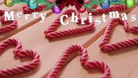 Animation-of-merry-christmas-text-over-candies-on-wooden-background