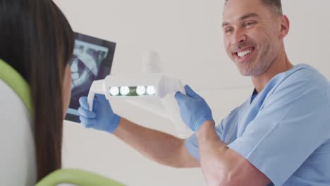 Lächelnder-Kaukasischer-Männlicher-Zahnarzt,-Der-Eine-Patientin-In-Einer-Modernen-Zahnklinik-Vorbereitet