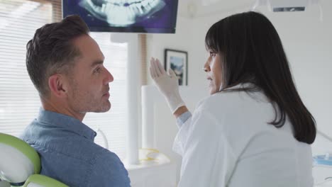 Biraziale-Zahnärztin-Mit-Gesichtsmaske-Bereitet-Männlichen-Patienten-In-Moderner-Zahnklinik-Vor