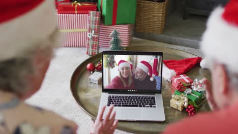 Senior-caucasian-couple-using-laptop-for-christmas-video-call-with-smiling-couple-on-screen
