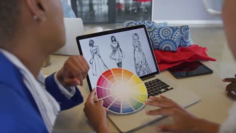 Diversos-Diseñadores-Femeninos-Y-Masculinos-Discutiendo-Diseños-De-Moda-En-Una-Computadora-Portátil-Y-Una-Rueda-De-Color-En-El-Estudio
