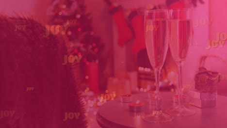 Animation-of-joy-text-on-red,-over-two-glasses-of-champagne,-with-christmas-presents-and-decorations