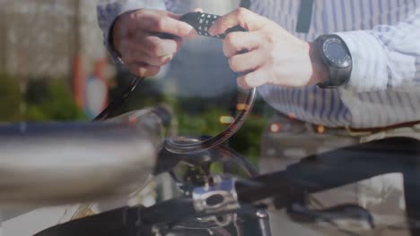 Animation-of-street-over-hands-of-caucasian-man-fastening-padlock-on-bike