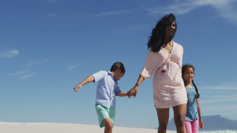 Happy-hispanic-mother-walking-with-daughter-and-son-on-beach