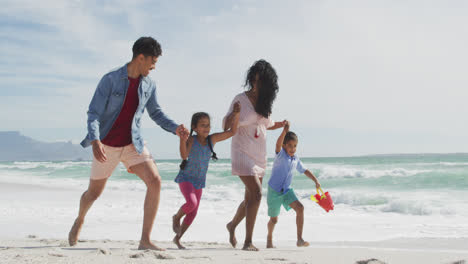 Happy-hispanic-mother,-father,-son-and-daughter-walking-and-playing-on-beach