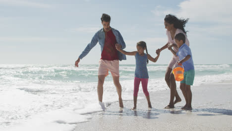 Happy-hispanic-mother,-father,-son-and-daughter-playing-in-sea-at-the-beach