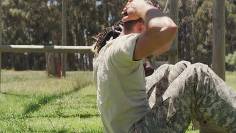 Diverse-fit-group-of-soldiers-doing-sit-ups-in-field,-at-army-obstacle-course-in-the-sun