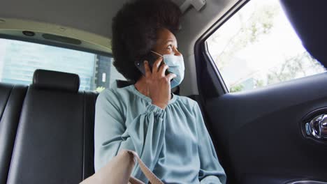 Afroamerikanische-Geschäftsfrau-Mit-Gesichtsmaske,-Die-Auf-Dem-Smartphone-Spricht