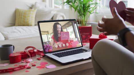 Happy-biracial-woman-with-vitiligo-reading-valentine-card-on-valentine's-day-video-call-on-laptop