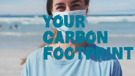 Animation-of-your-carbon-footprint-text-in-blue-over-caucasian-woman-in-face-mask-on-beach