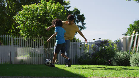 Glücklicher-Gemischtrassiger-Mann-Und-Sein-Sohn-Spielen-Fußball-Im-Garten