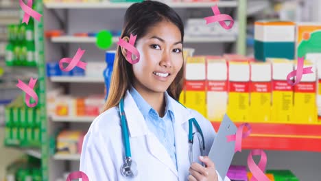 Animation-of-breast-cancer-awareness-ribbons-over-asian-female-doctor