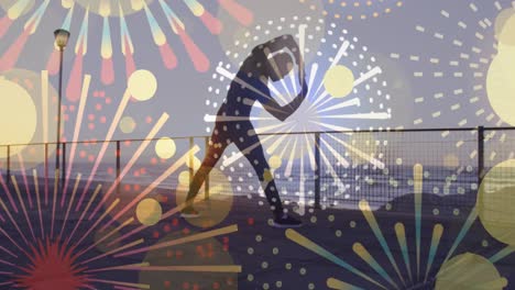Fireworks-icons-against-african-american-fit-man-performing-stretching-exercise-at-the-promenade